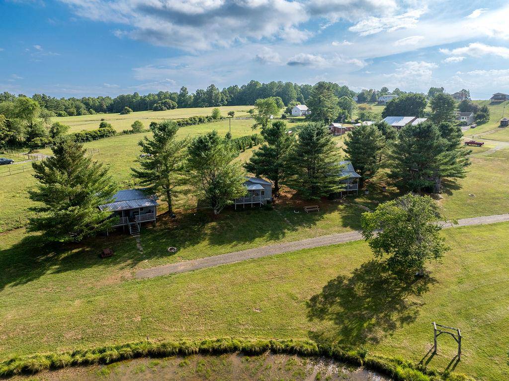 Aerial of open pasture with the small cabins, a pond and a barn.